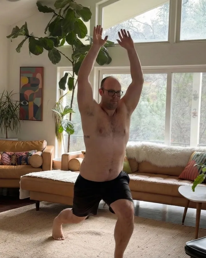Spencer mid-routine in his living room, arms overhead